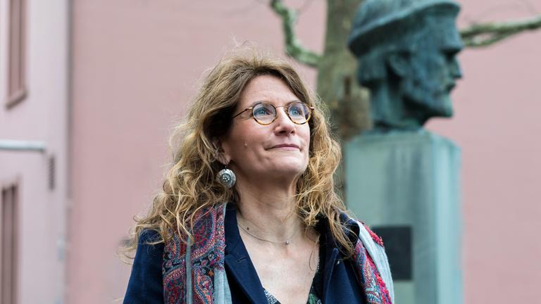 Anna Katharina Hahn steht vor der Büste von Johannes Gutenberg vor dem Gutenberg Museum in Mainz.