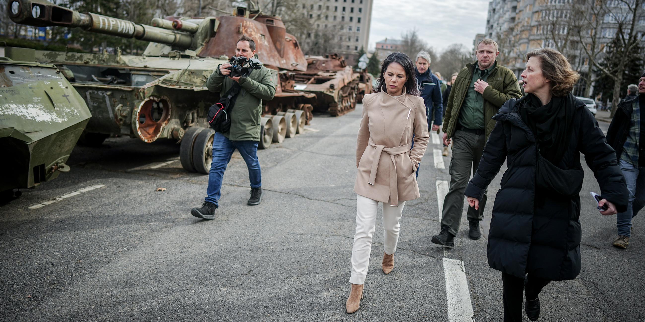 Annalena Baerbock geht bei ihrem Besuch des ehemaligen Sitz der Regionalverwaltung der Oblast Mykolajiw an zerstörten russischen Panzern vorbei am 25.02.2024.