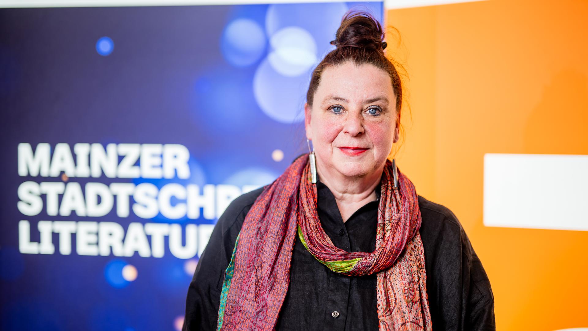 Frau lächelt auf einer Bühne in die Kamera.