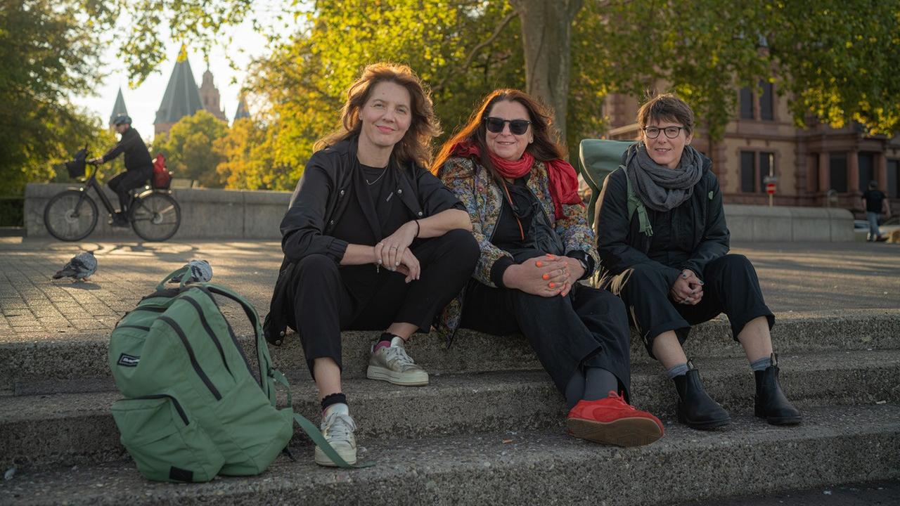 Schriftstellerinnen Peggy Mädler, Annett Gröschner (Mainzer Stadtschreiberin) und Wenke Seemann (von links nach rechts) sitzen auf der Rheintreppe in Mainz. 