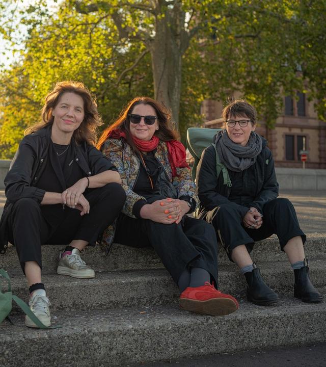Schriftstellerinnen Peggy Mädler, Annett Gröschner (Mainzer Stadtschreiberin) und Wenke Seemann (von links nach rechts) sitzen auf der Rheintreppe in Mainz. 