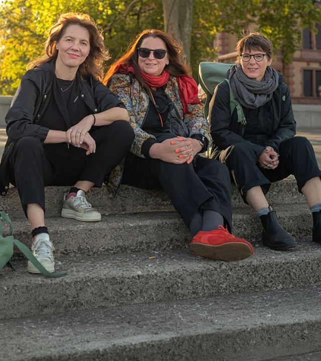 Schriftstellerinnen Peggy Mädler, Annett Gröschner (Mainzer Stadtschreiberin) und Wenke Seemann (von links nach rechts) sitzen auf der Rheintreppe in Mainz. 