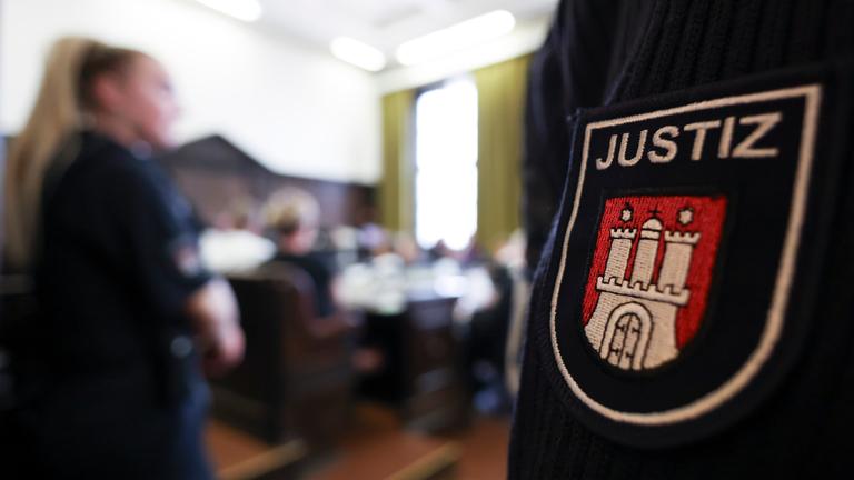 Mann mit Justizuniform. Abgebildet ist das Hamburger Wappen