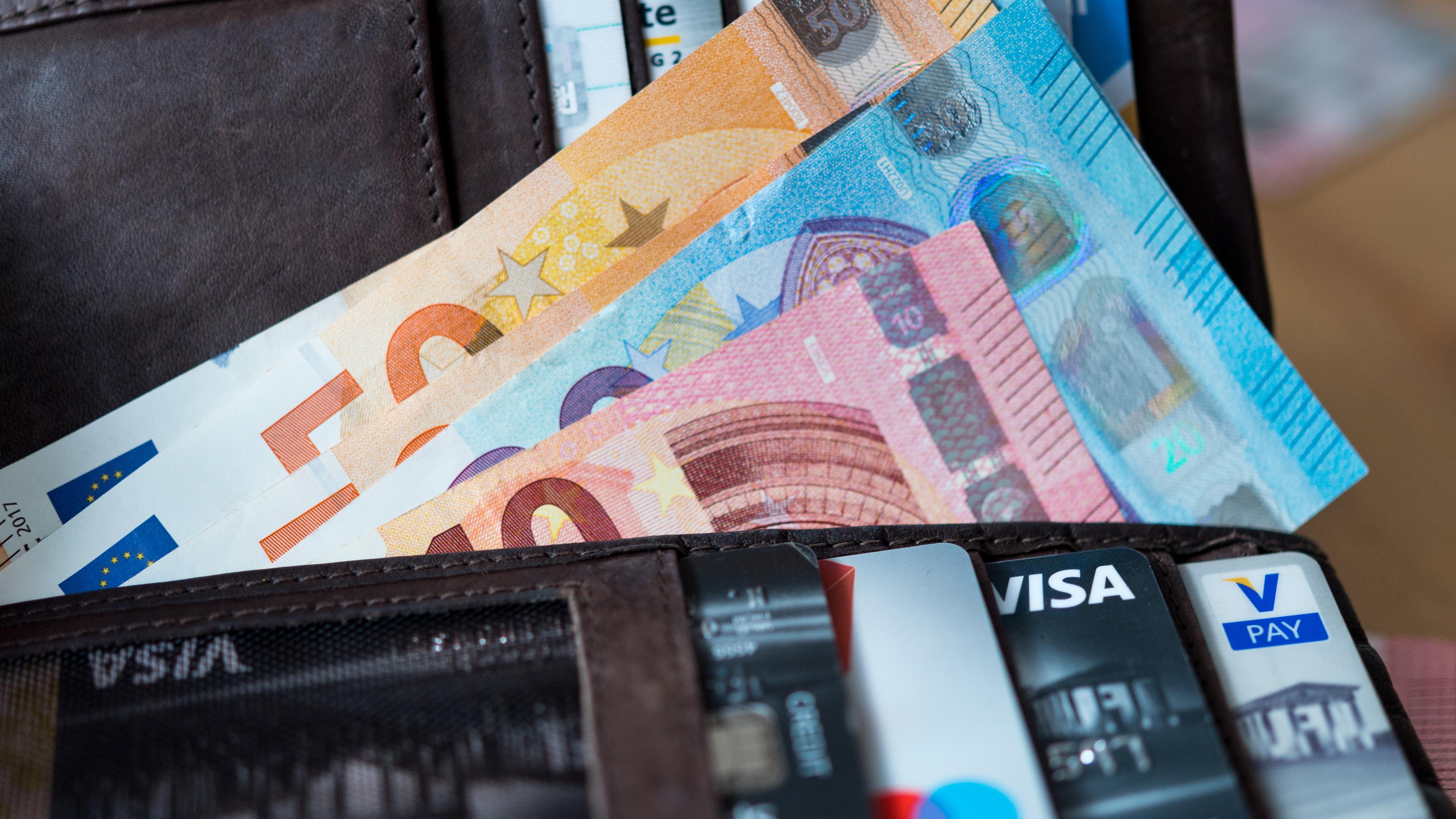Banknoten und Bankkarten liegen in einer Geldbörse.