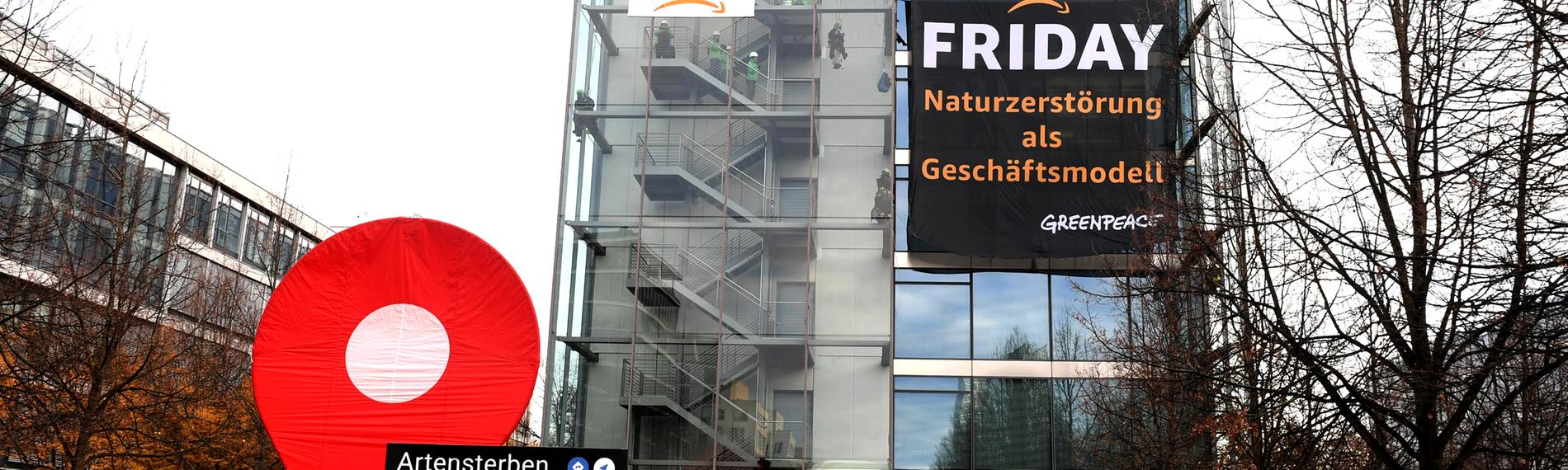 Greenpeace-Aktive protestieren während der Rabattaktion Black Friday gegen die Ressourcenverschwendung des Online-Versandhändlers Amazon am Amazon Deutschland Gebäude und hängen dort Plakate auf mit der Aufschrift "crime" und "Black Friday - Naturzerstörung als Geschäftsmodell".