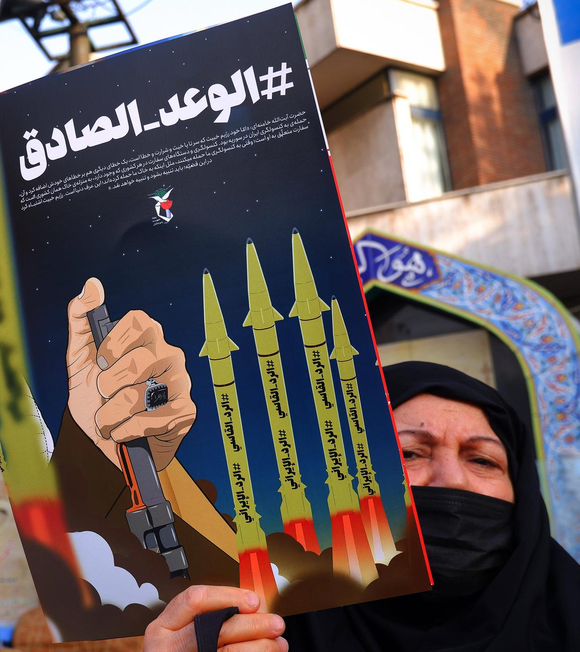 Eine iranische Regierungsbefürworterin hält ein Anti-Israel-Plakat im Zentrum Teherans