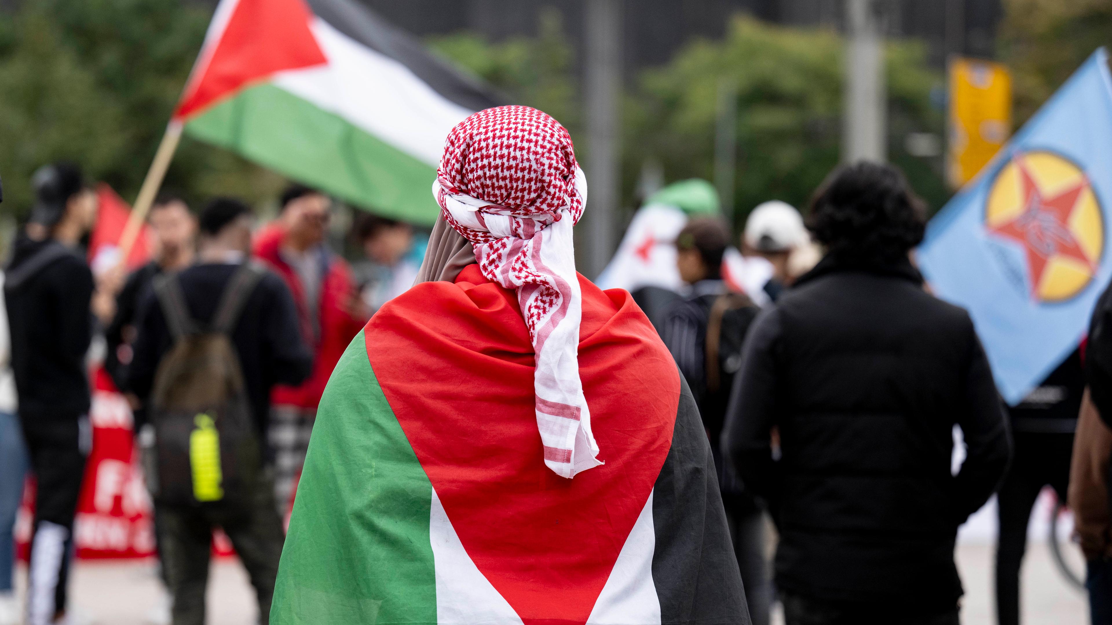 Teilnehmer einer Kundgebung im Zentrum von Leipzig tragen palästinensische Flaggen. 