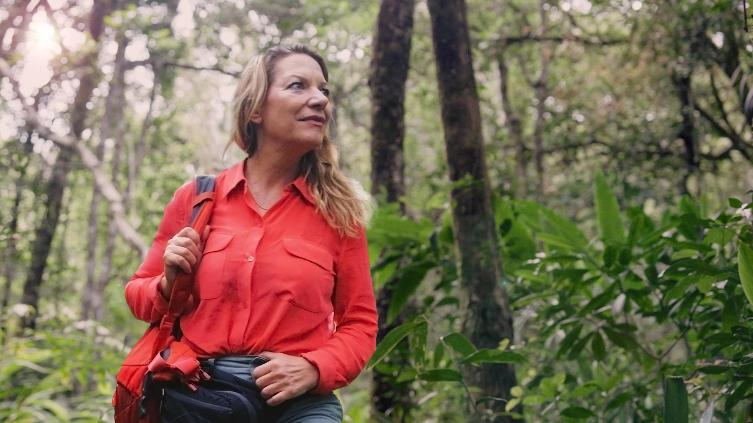 Die Systemforscherin Antje Boetius steht im Regenwald. Sie trägt eine große Umhängetasche und schaut zur Seite.