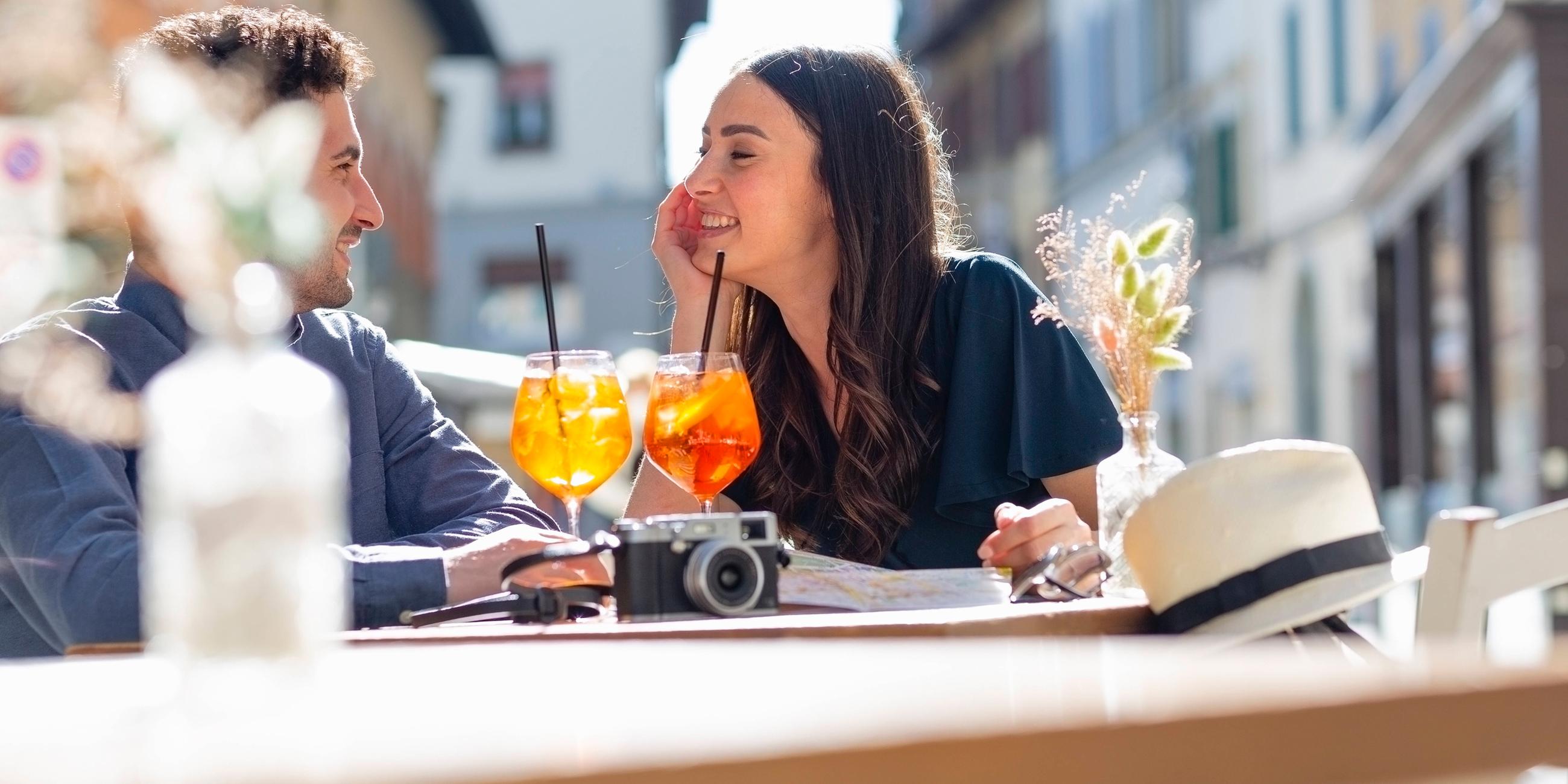 Paar sitzt mit Getränken in einem Straßencafé