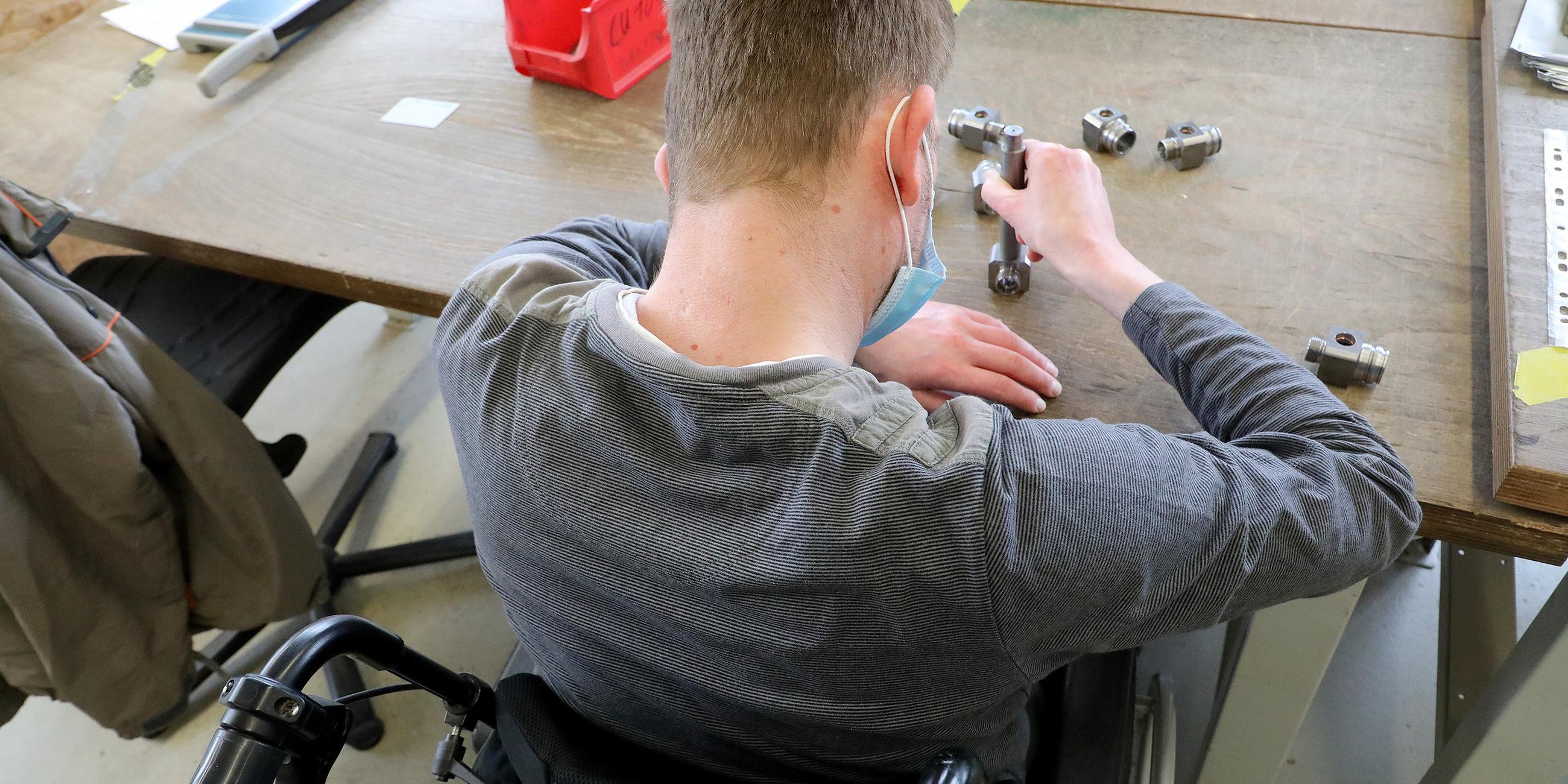 Mann im Rollstuhl arbeitet in einer Metallabteilung