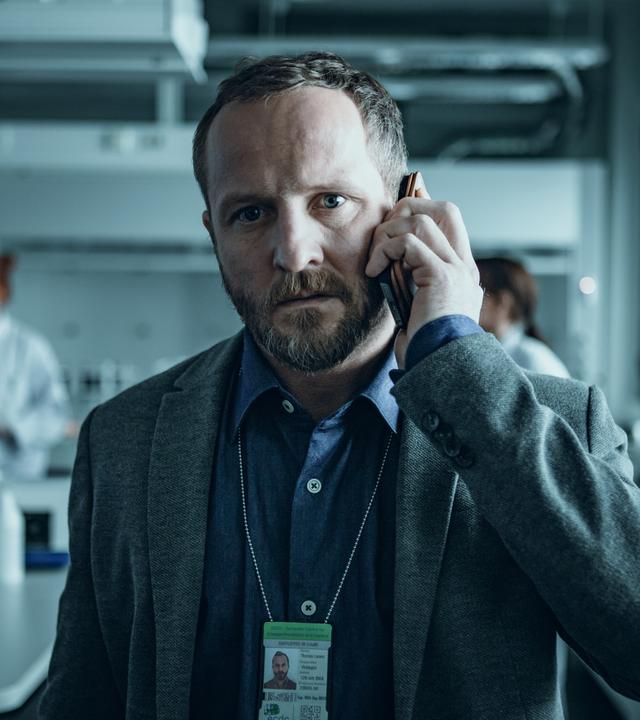 "Arctic Circle - Der unsichtbare Tod (2)": Dr. Thomas Lorenz (Maximilian Brückner) in Nahaufnahme. Er steht telefonierend in einem Labor.