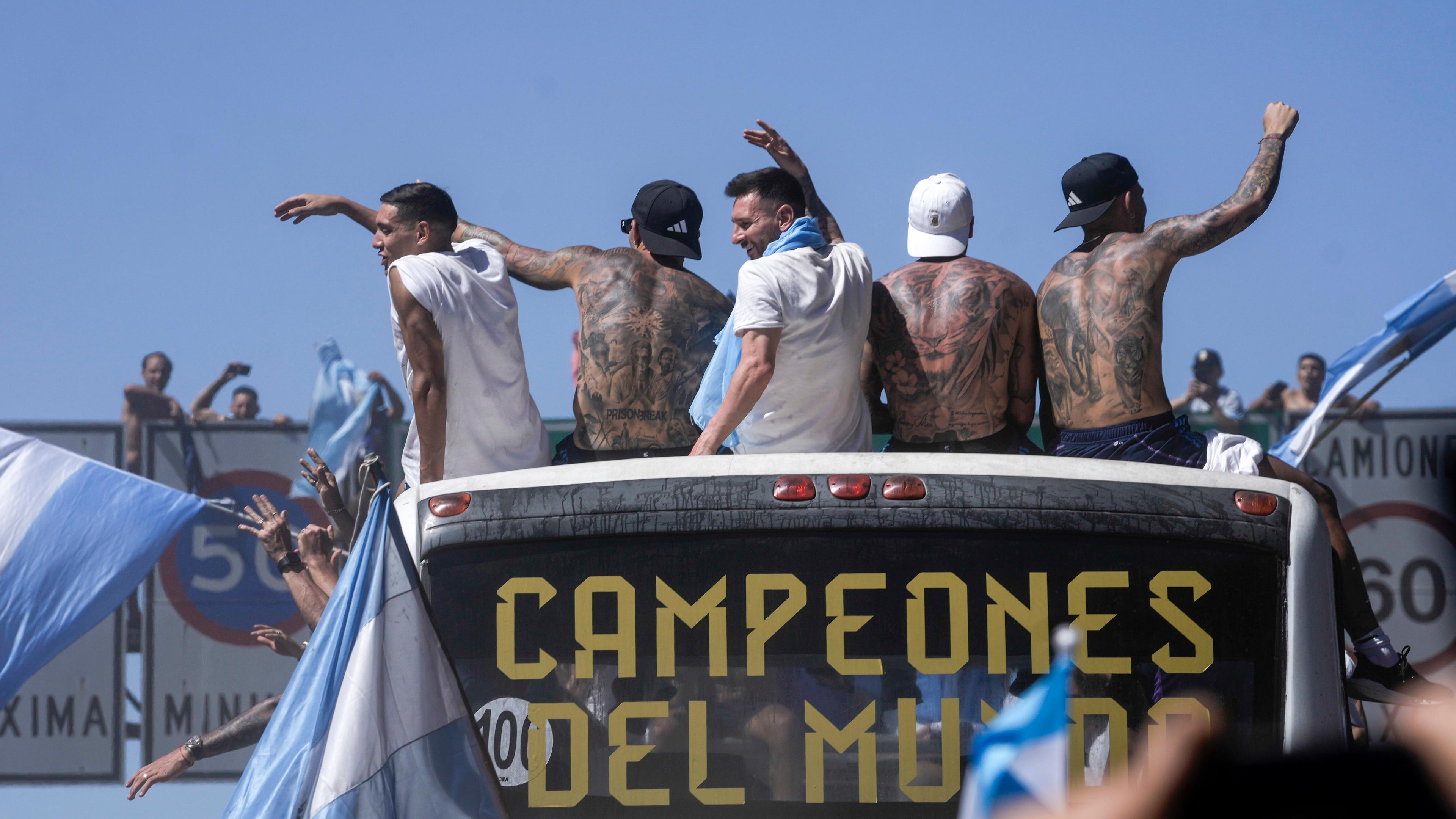 Argentinien, Buenos Aires: Fußball, WM: Nach der Ankunft von Weltmeister Argentinien in der Heimat: Lionel Messi (M.) und seine Kameraden der argentinischen Fußballmannschaft fahren auf einem offenen Bus während ihrer Heimkehrparade.