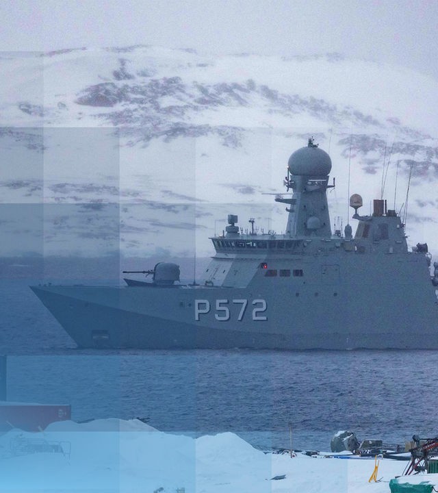 Ein Militärschiff in der Arktis. Im Hintergund ist ein schneebedeckter Berg.