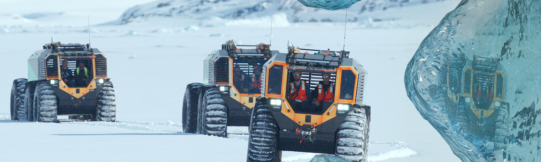 Drei große Schneefahrzeuge fahren hintereinander in einer schneebedeckten Landschaft.