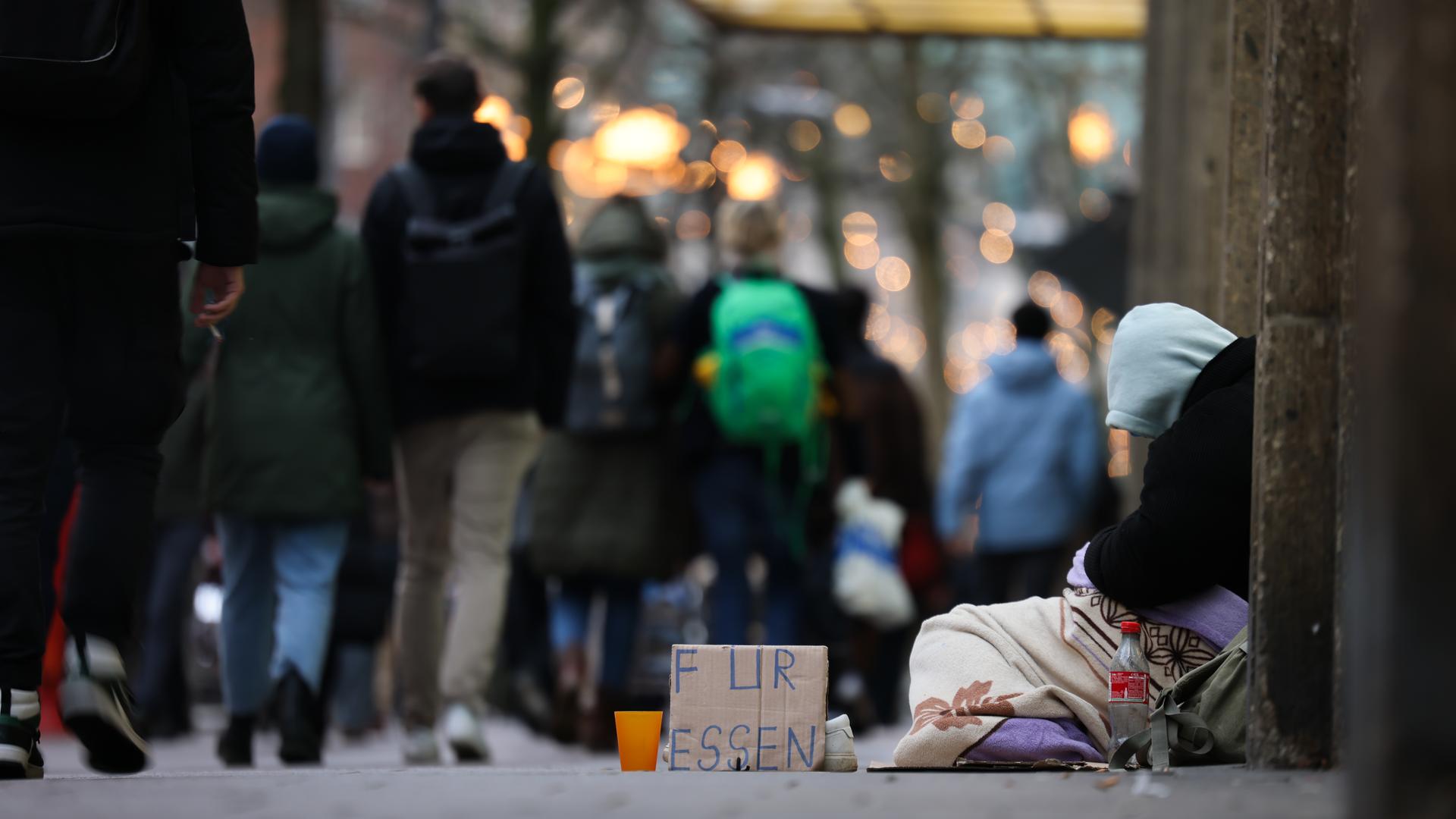  Ein Mensch bittet um finanzielle Hilfe «für Essen» in der weihnachtlich dekorierten Mönckebergstraße.