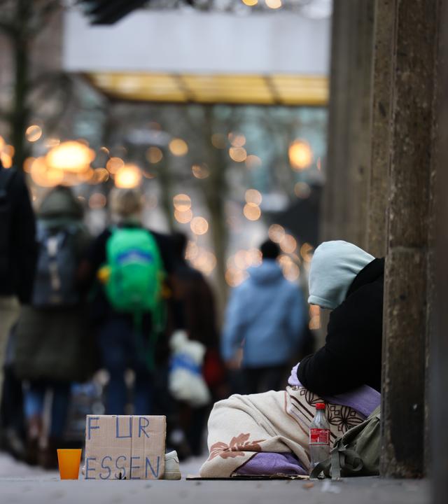  Ein Mensch bittet um finanzielle Hilfe «für Essen» in der weihnachtlich dekorierten Mönckebergstraße.