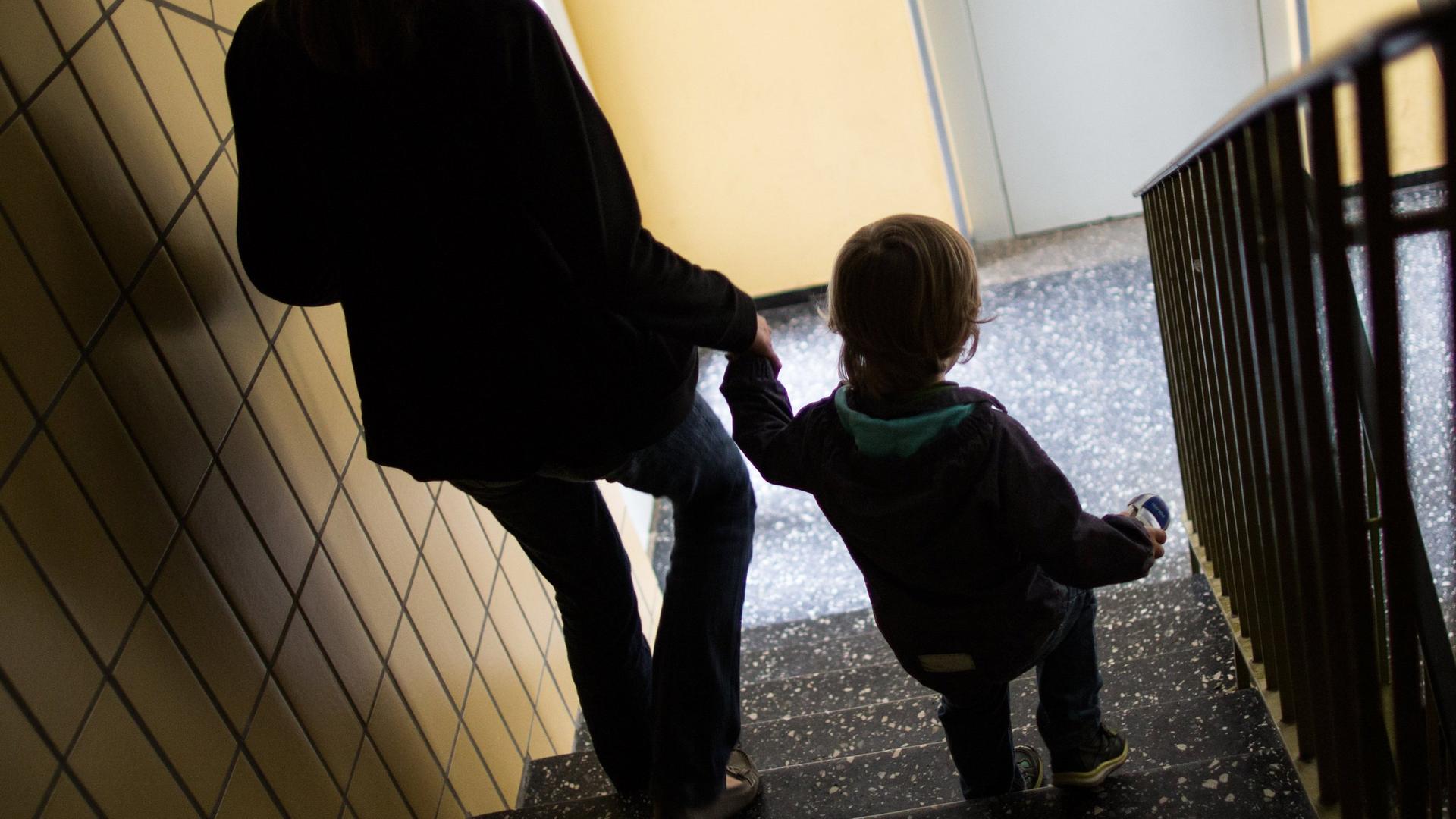 Gegenlicht: Mutter geht mit ihrem Kind die Treppe runter in einem Sozialbau