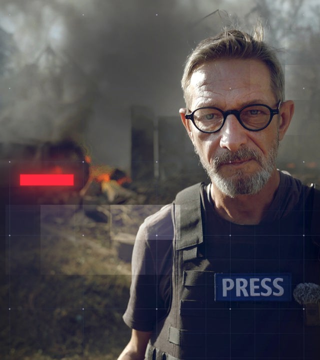 frontal-Reporter Arndt Ginzel mit schusssicherer Weste vor brennendem Autofrack, das durch einen Drohnenangriff in der Ukraine zerstört wurde 