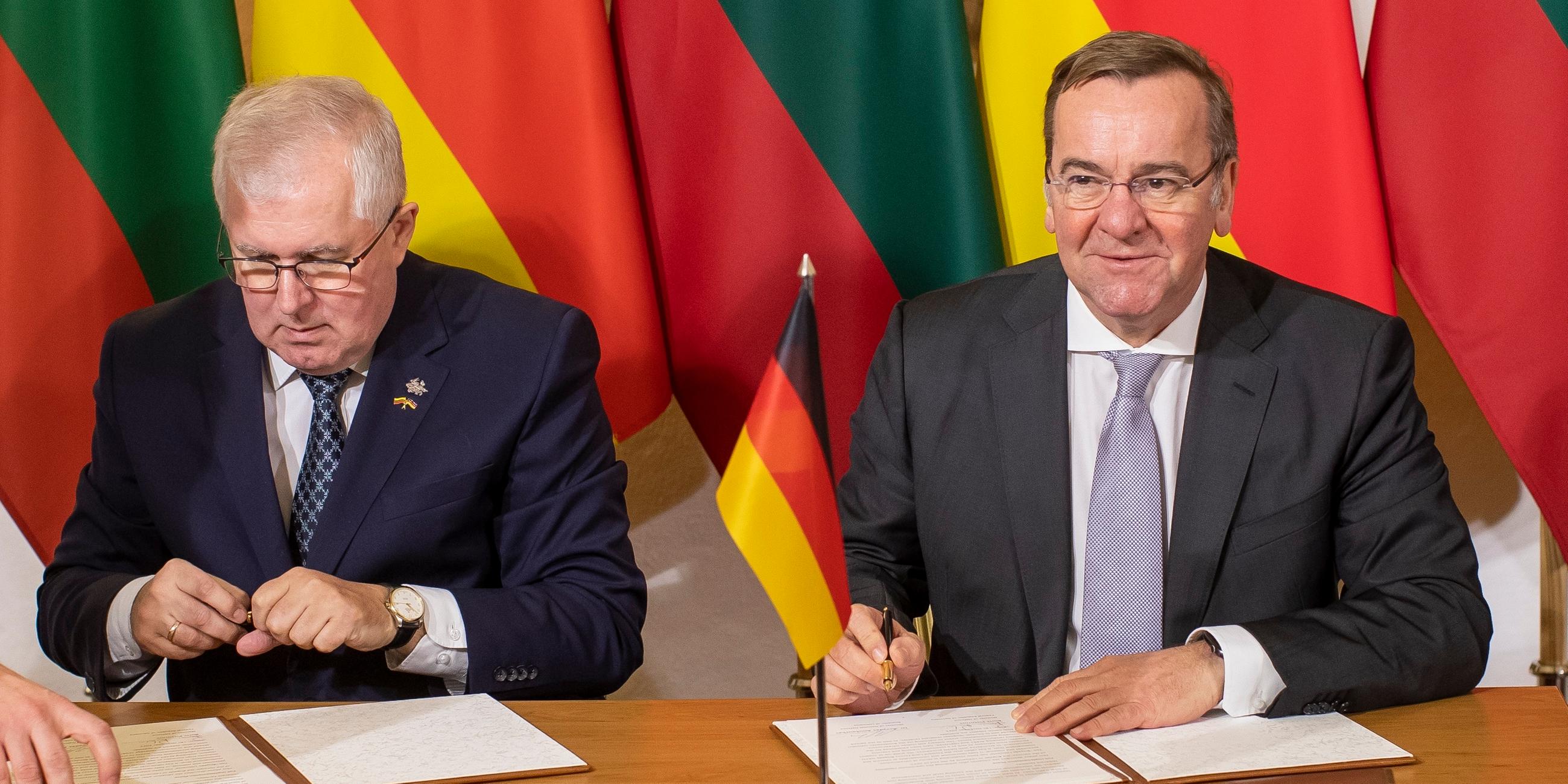 Arvydas Anusauskas und Boris Pistorius, unterzeichnen während ihres Treffens im Verteidigungsministerium in Vilnius, am 18.12.2023, einen litauisch-deutschen Aktionsplan