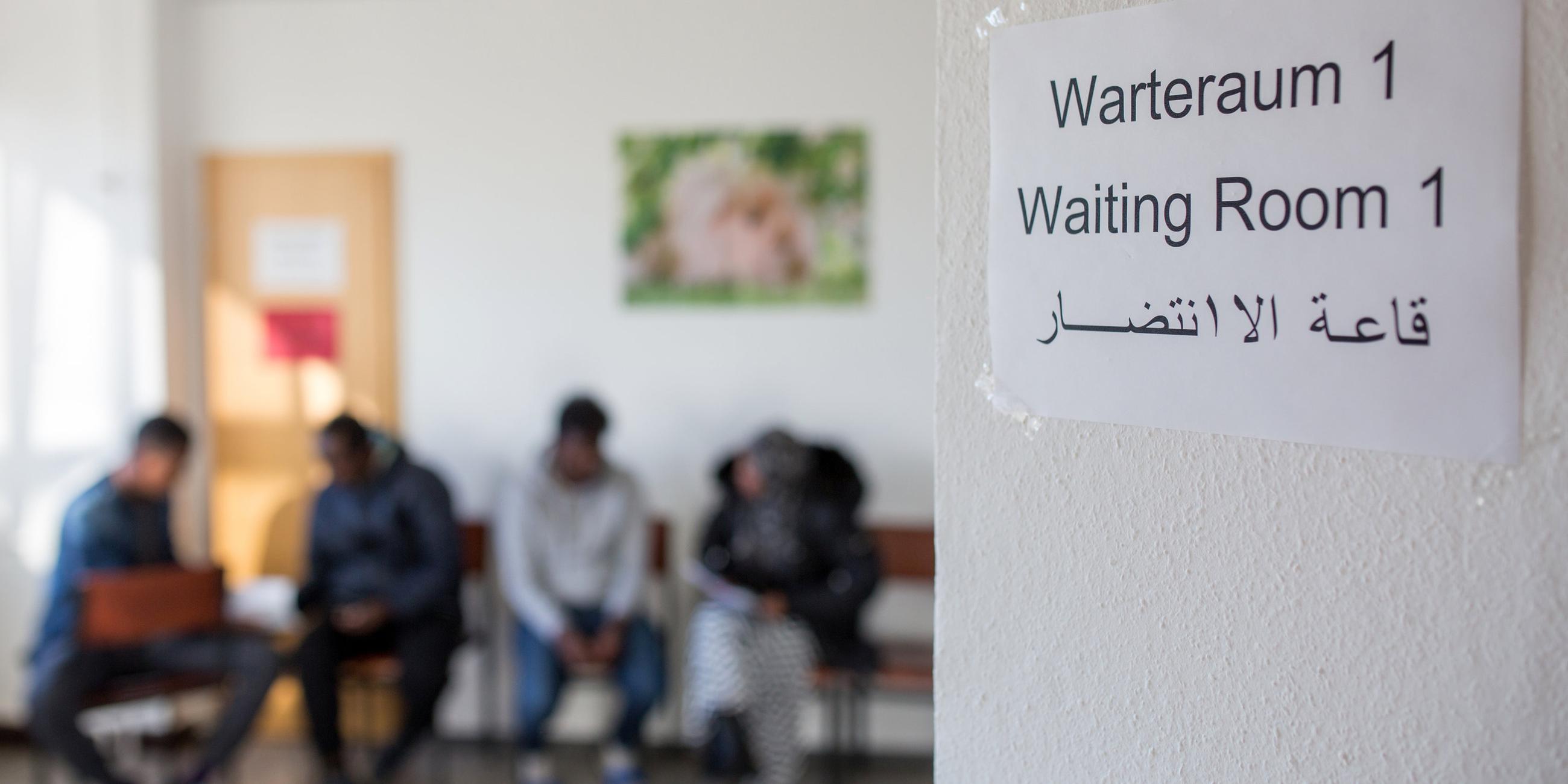 Wartezimmer mit Hinweisschild für Asylbeantragende