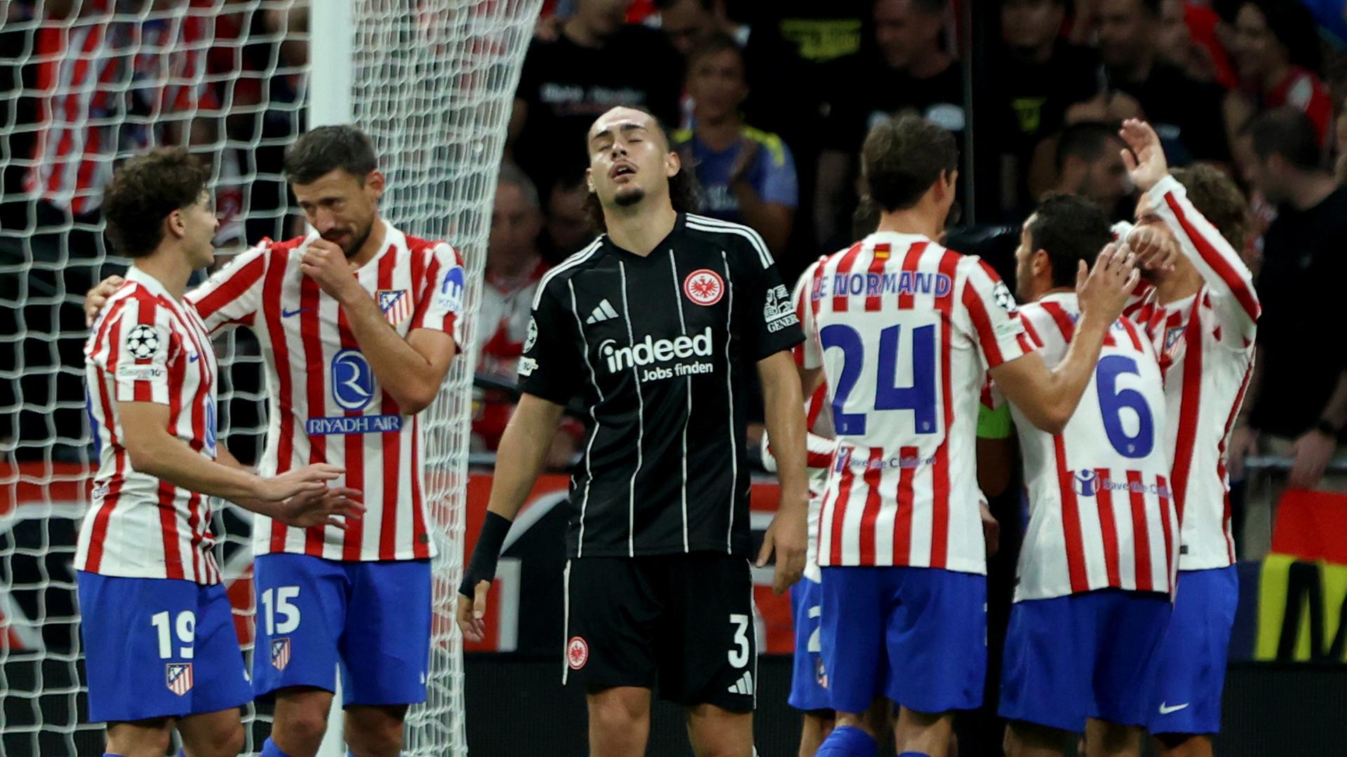 Atletico Madrid - Eintracht Frankfurt: Arthur Theate steht bedrückt auf dem Platz, während im Hintergrund Atletico-Spieler jubeln.