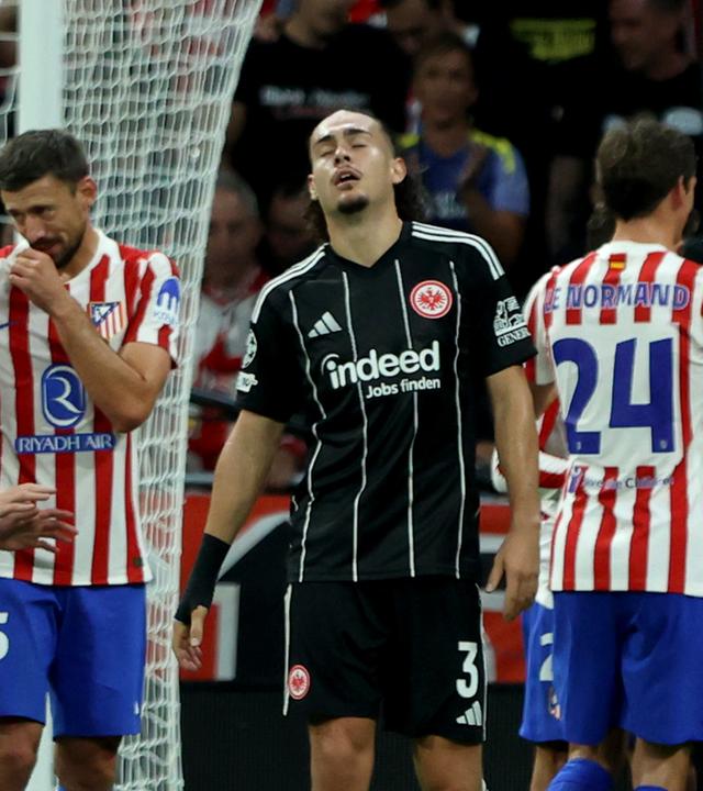 Atletico Madrid - Eintracht Frankfurt: Arthur Theate steht bedrückt auf dem Platz, während im Hintergrund Atletico-Spieler jubeln.