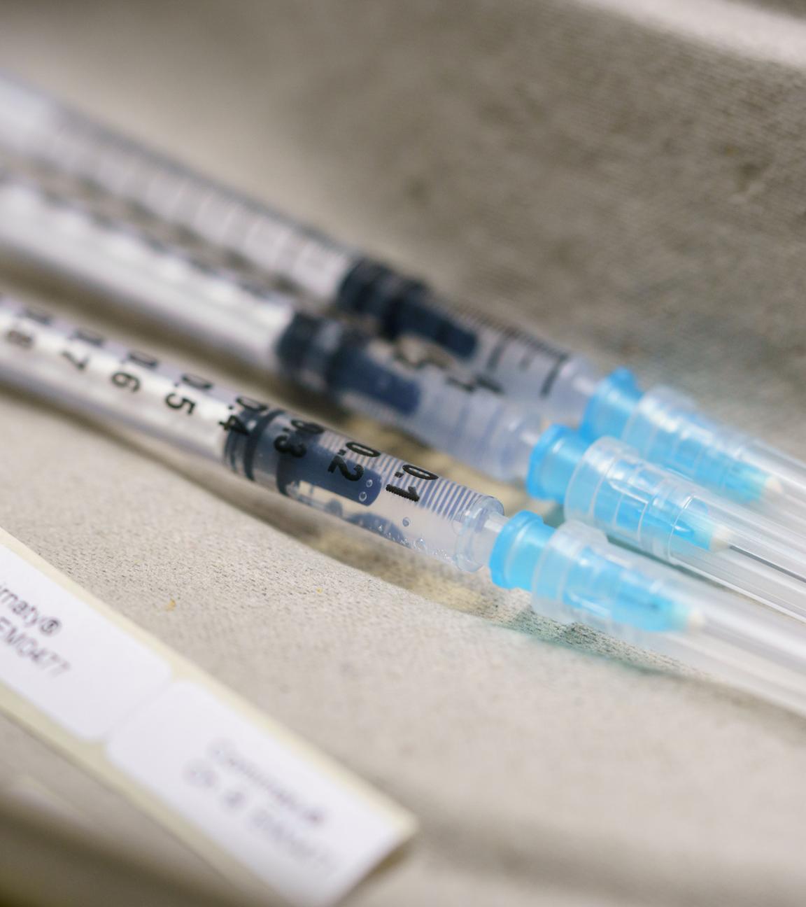 3 Spritzen mit dem Coronaimpfstoff liegen auf einem Tisch