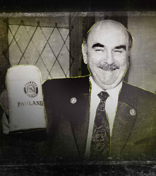 Ein Mann mit Schnurrbart, breit grinsend und einen gefüllten Bierkrug in der Hand