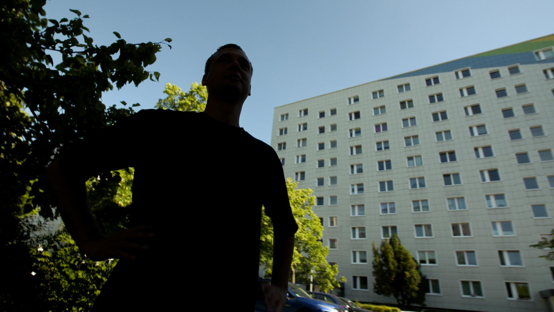 Schattenriss eines Mannes vor Plattenbau