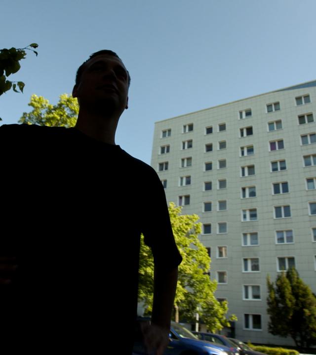 Schattenriss eines Mannes vor Plattenbau