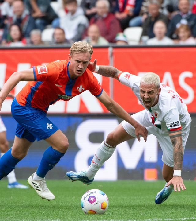 Augsburgs Philip Tietz im Zweikampf mit Darmstadts Christoph Klarer am 07.10.2023.