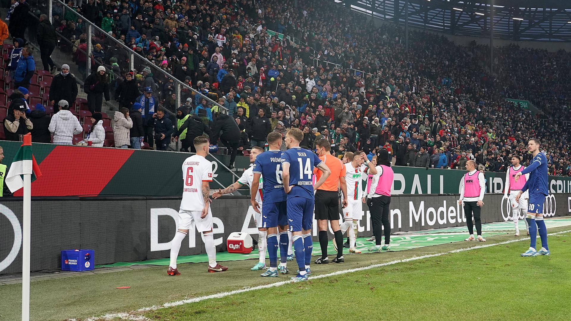 Beide Mannschaften und Schiedsrichter Dr. Felix Brych stehen am 11.11.2023 nach einem Böllerwurf aus dem Hoffenheimer Fanblock vor der Tribüne.