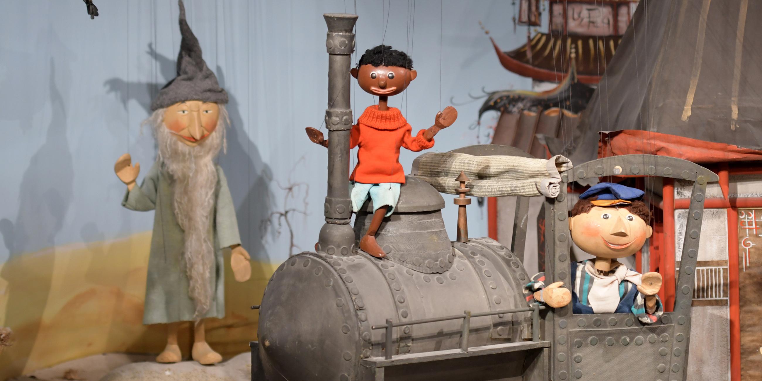"Jim Knopf" und "Lukas" stehen zusammen mit der Lokomotive "Emma" im Puppentheatermuseum