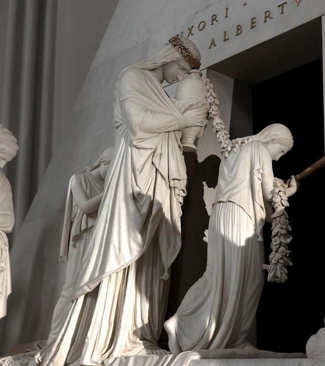 Canova-Denkmal in der Augustinerkirche in Wien. Dargestellt sind mehrere Figuren aus weißem Marmor, die tief in eine szenische Darstellung involviert sind. 