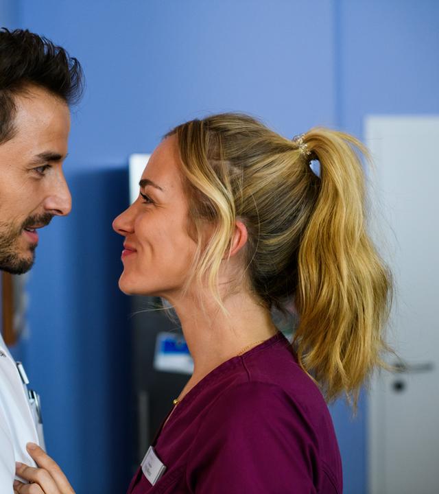 "Bettys Diagnose - Alles nur aus Liebe": Dr. Frank Stern (Max Alberti) und Betty Weiss (Annina Hellenthal) stehen sich im Klinikflur dicht gegenüber und schauen sich lächelnd in die Augen.