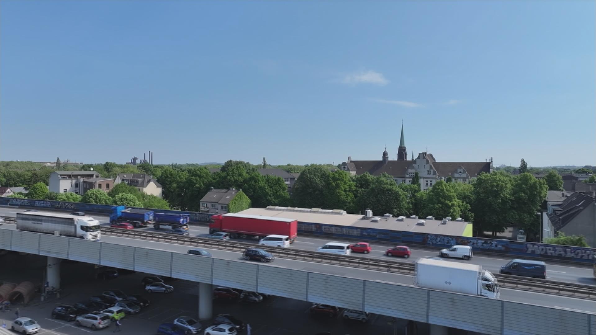 Stark befahrene Autobahnbrücke führt durch Wohngebiet.