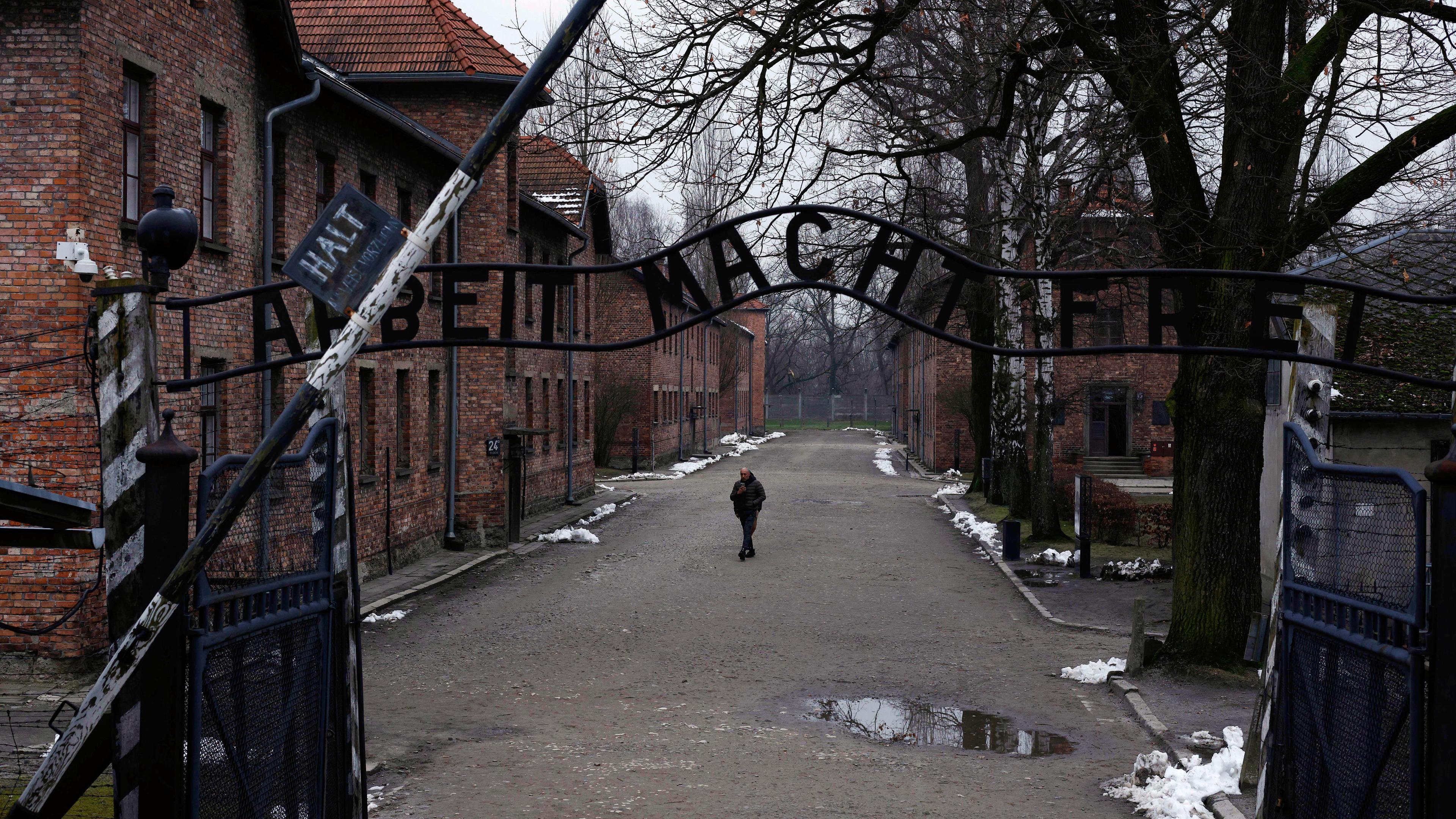 Eine Person läuft durch das Tor von Auschwitz.