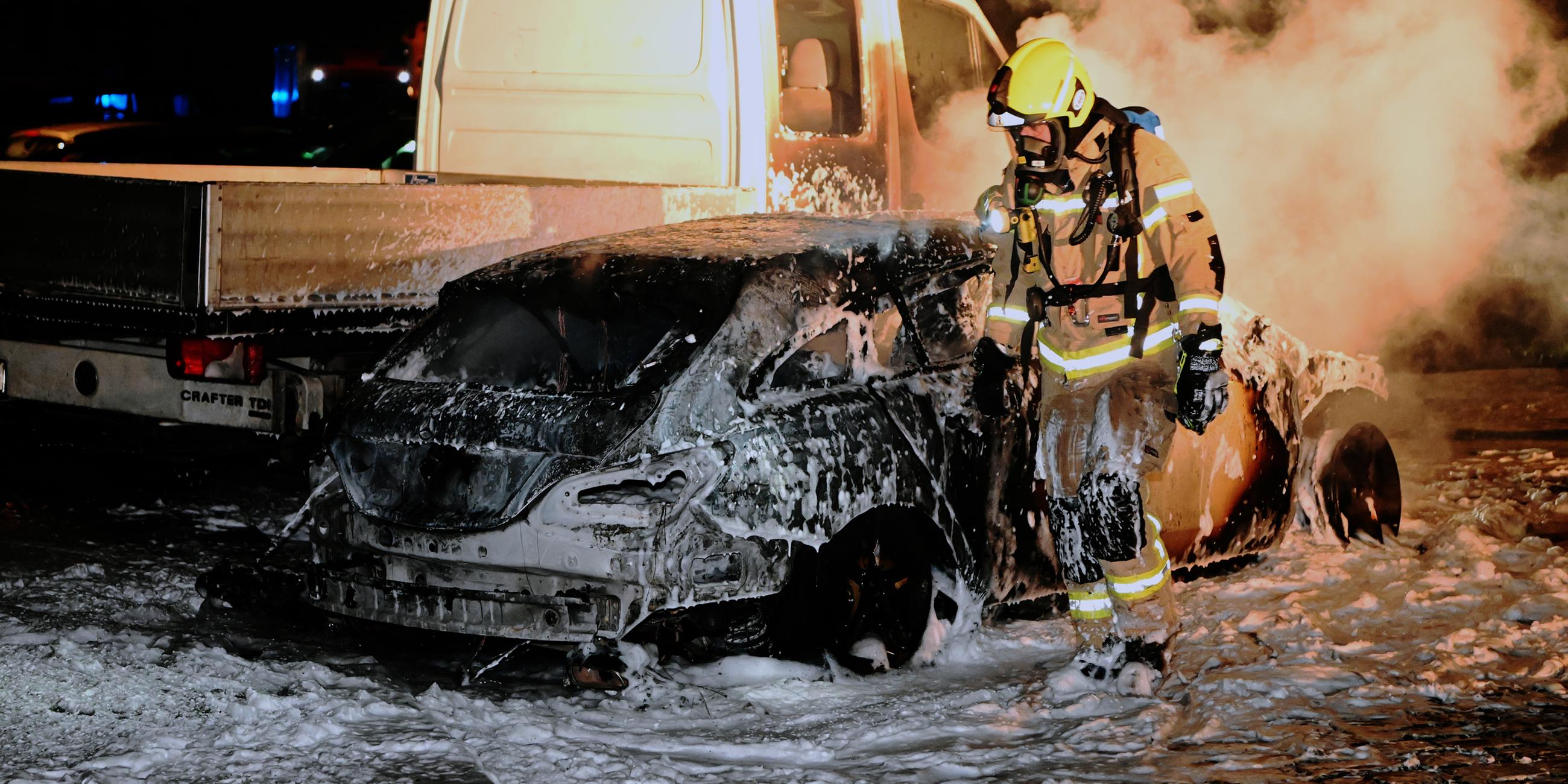 Ein Feuerwehrmann geht im Berliner Stadtteil Moabit an einem zerstörten Auto vorbei.