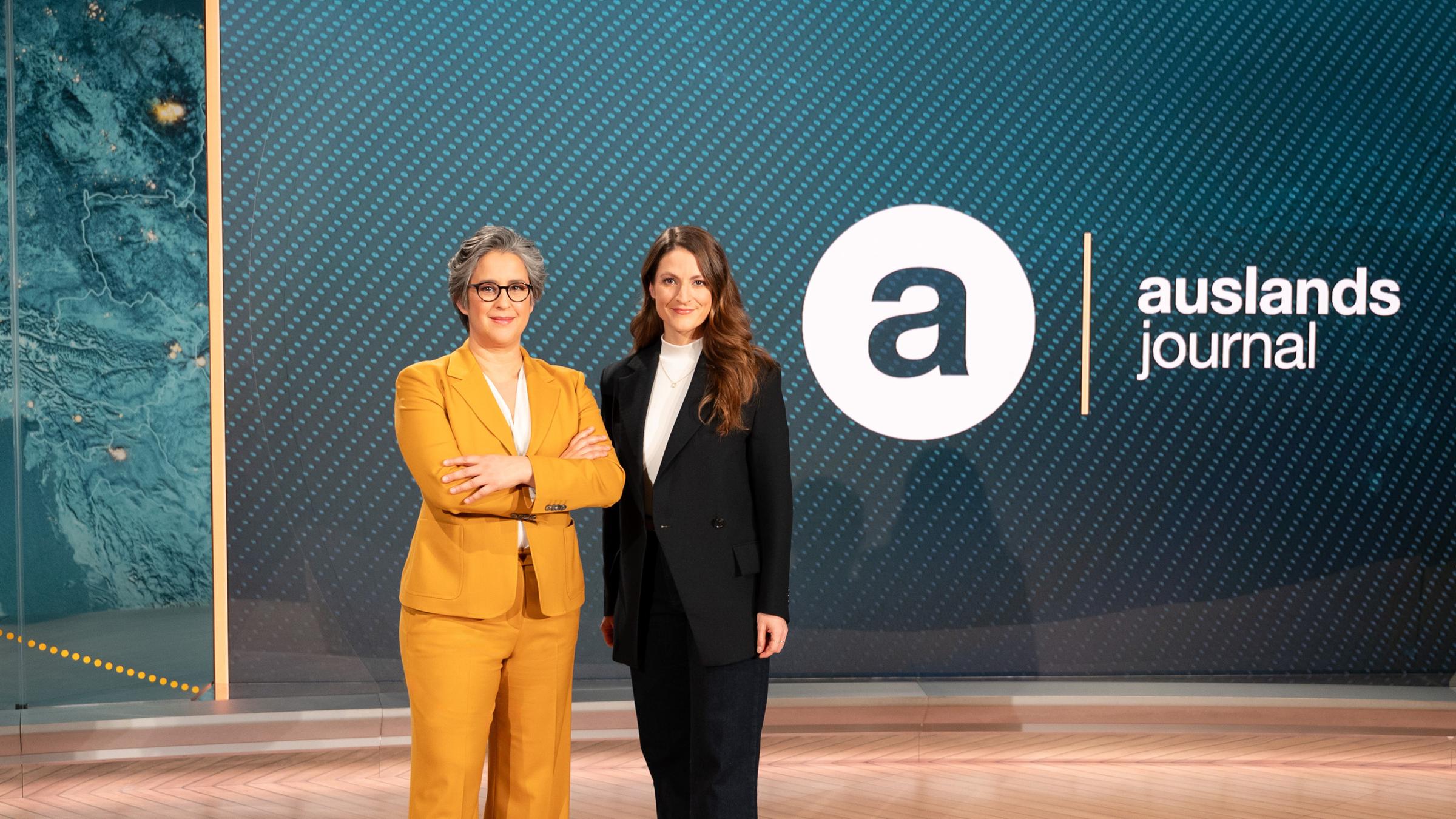 Die Moderatorinnen des ZDF-"auslandsjournal": Shakuntala Banerjee und Alica Jung stehen neben dem Sendelogo