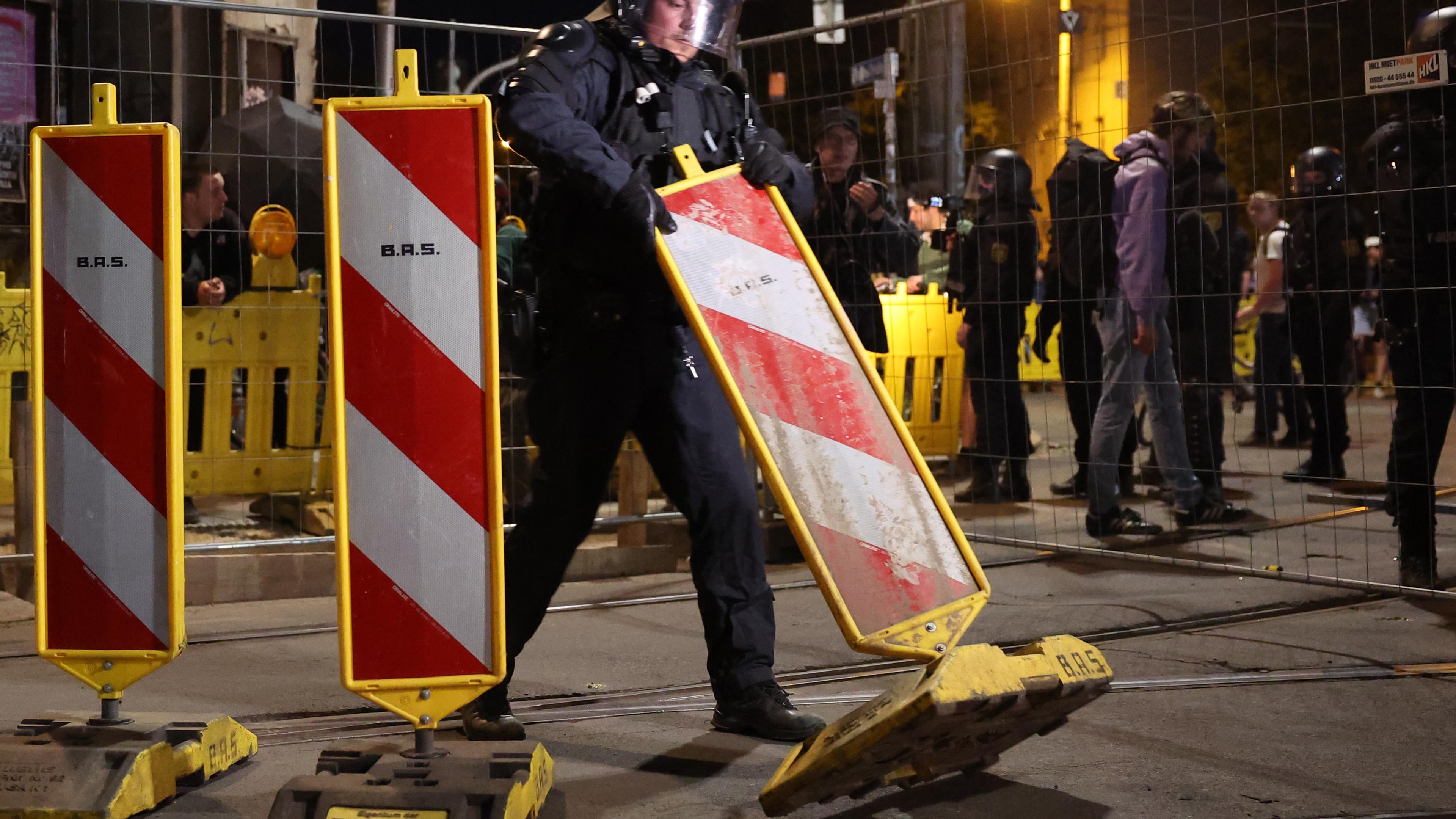 Ein Polizist räumt in Leipzig einen Signalpfosten um - im Hintergrund ein Absperrgitter: Nach der Urteilsverkündung gegen Lina E. gab es Ausschreitungen.