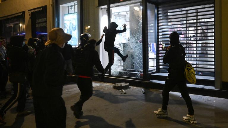 Vermummte Personen brechen in einen Laden in Paris ein. 
