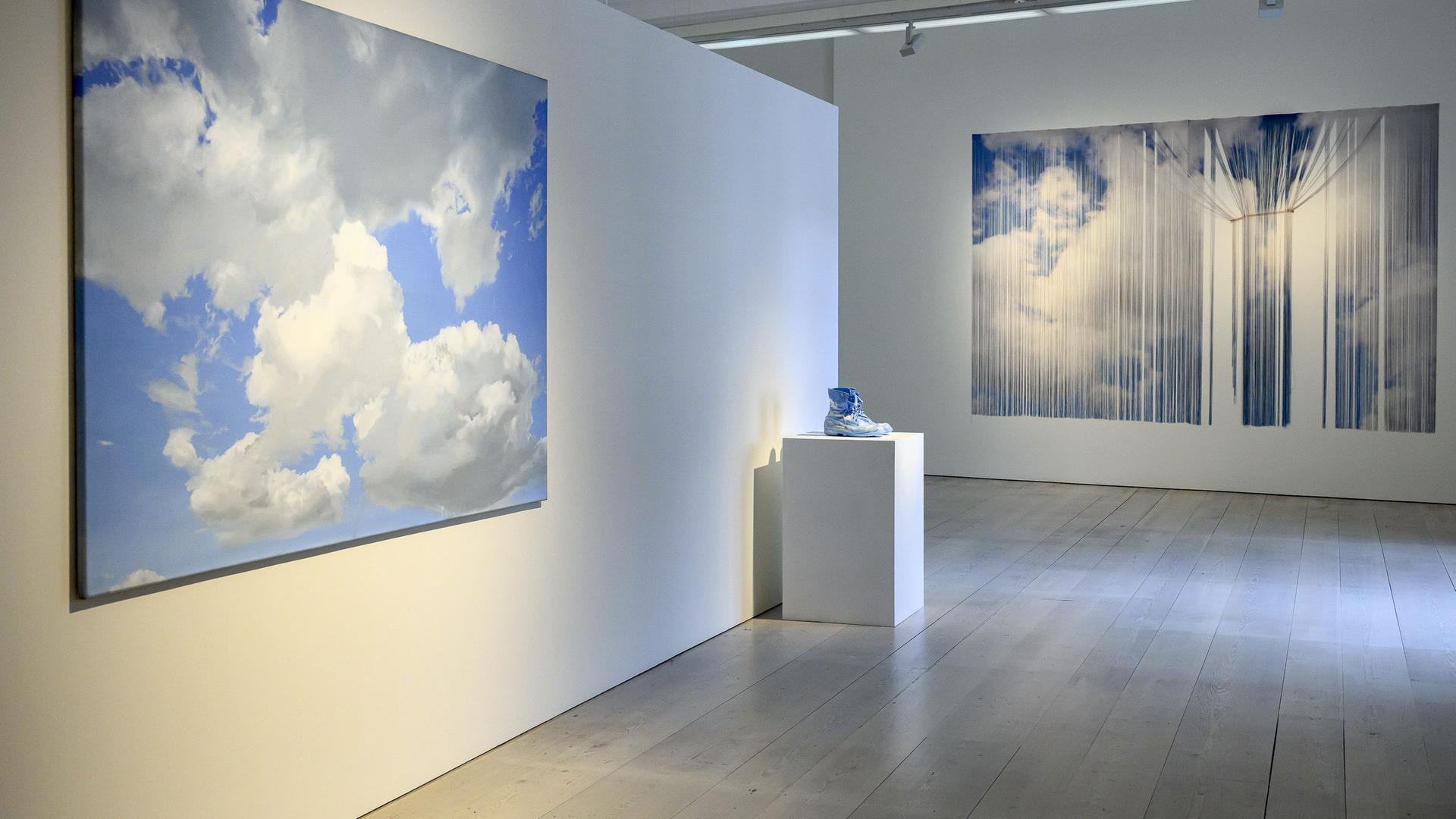 In einem Ausstellungsraum sieht man Exponate mit Wolkenmotiven.