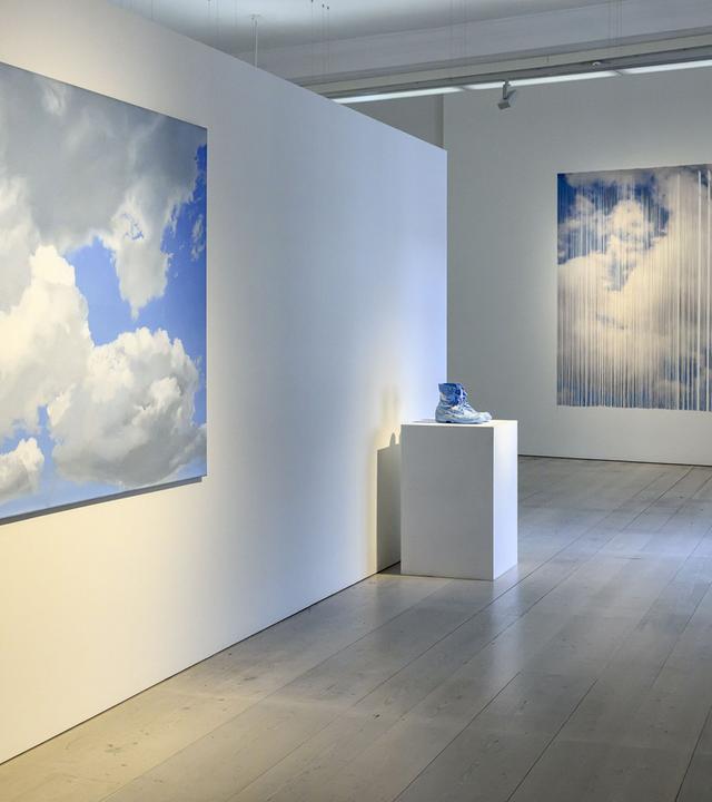In einem Ausstellungsraum sieht man Exponate mit Wolkenmotiven.