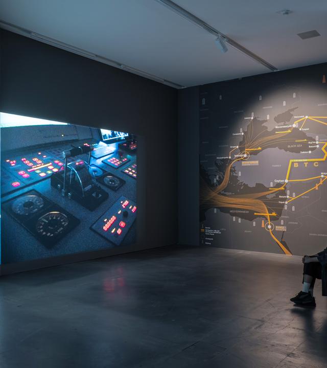 In einem Ausstellungsraum schaut sich eine Frau eine Videoinstallation an.