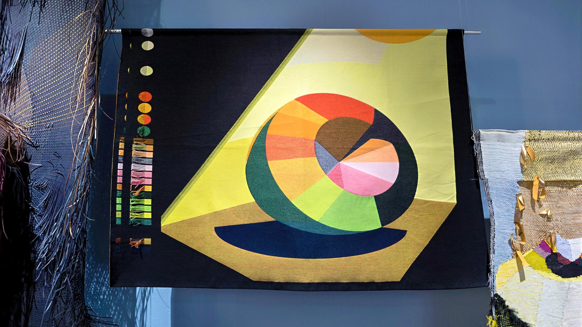 Man sieht die Installation eines modernen, bunten Kunstwerkes in einem Ausstellungsraum.