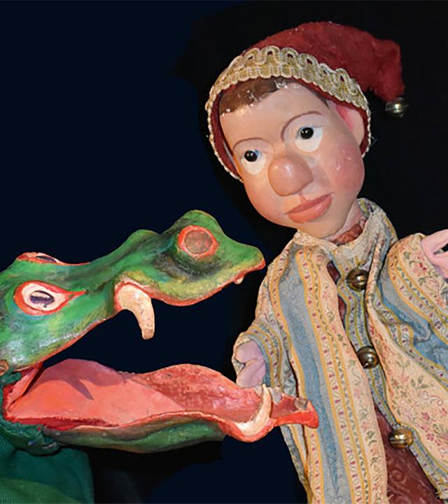 Eine Kasperl-Figur steht links neben einer Krokodils-Handpuppe.