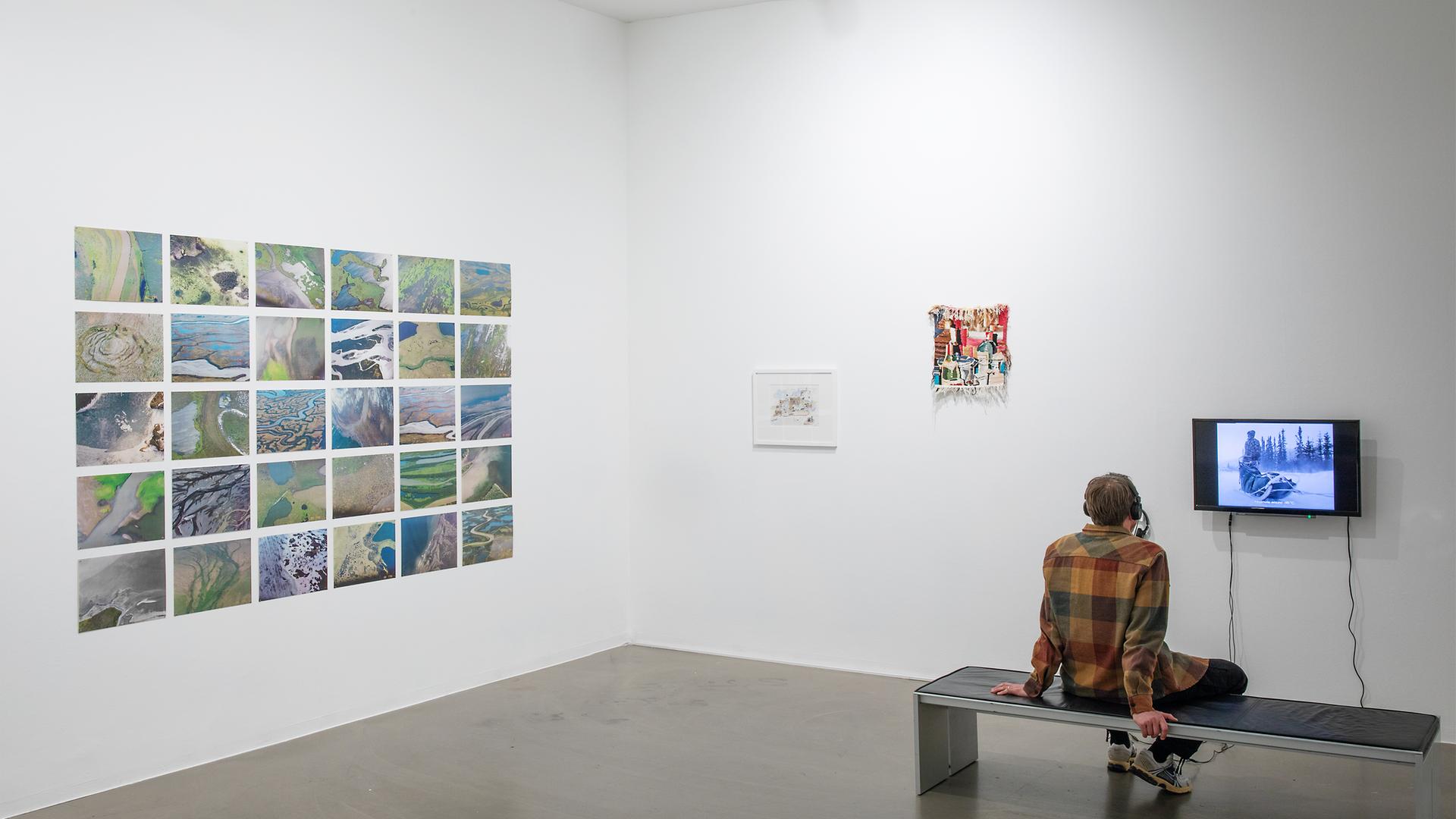 In einem Ausstellungsraum sitzt ein Mann der sich die Exponate ansieht. 