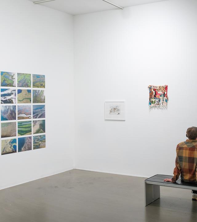 In einem Ausstellungsraum sitzt ein Mann der sich die Exponate ansieht. 