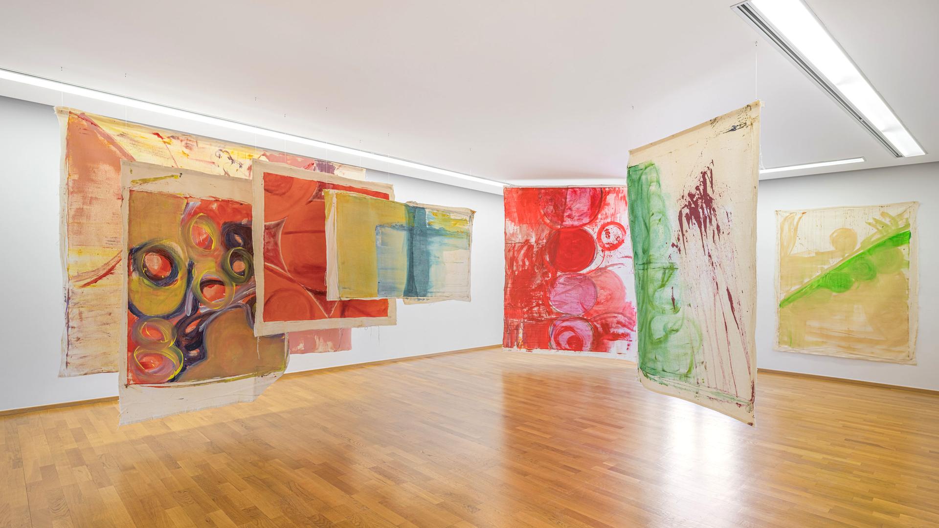 In einem Ausstellungsraum sind bunte, moderne Kunstwerke ausgestellt.