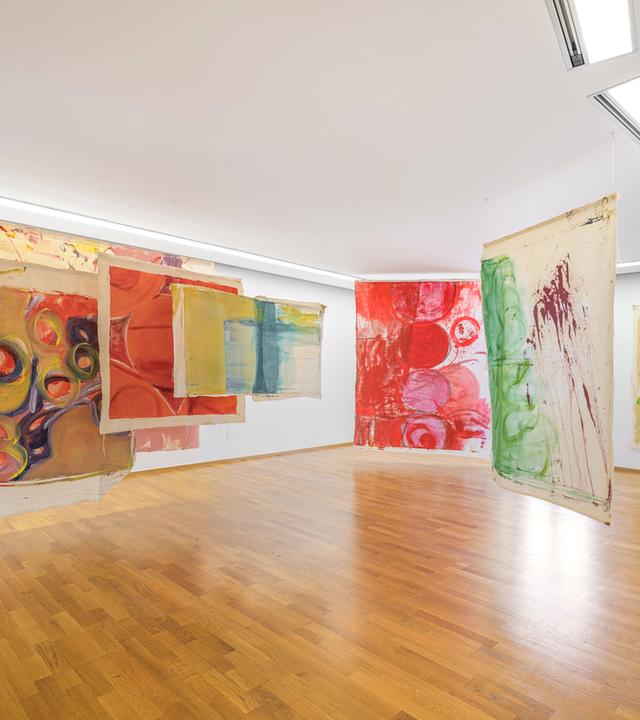 In einem Ausstellungsraum sind bunte, moderne Kunstwerke ausgestellt.